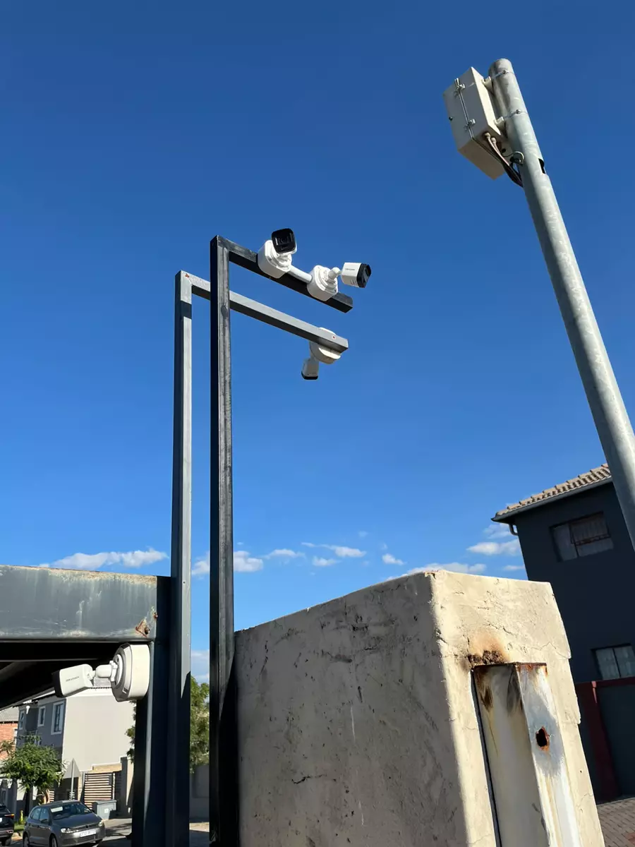 Security cameras mounted on poles against a blue sky
