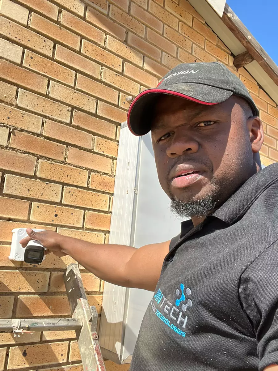 Technician installing equipment on a brick wall