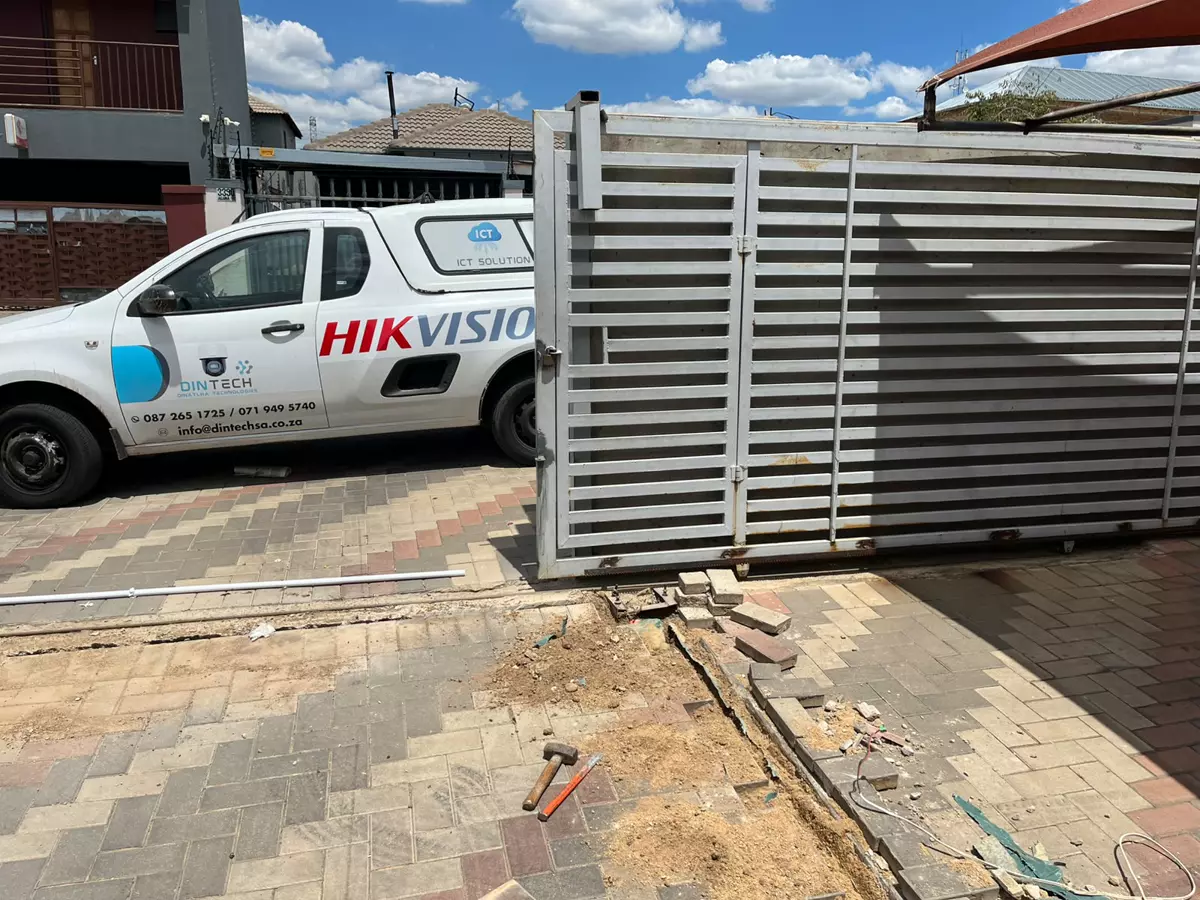 Service vehicle parked in a driveway next to a large metal gate